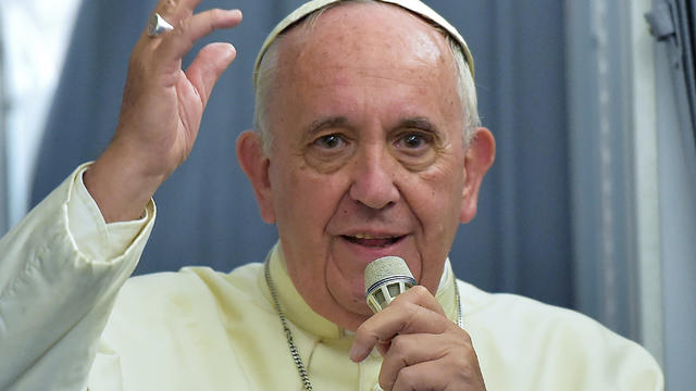 Pope Francis gestures to journalists during a press conference onboard a plane on his way back to Rome from Paraguay, the final stop of his South America tour 