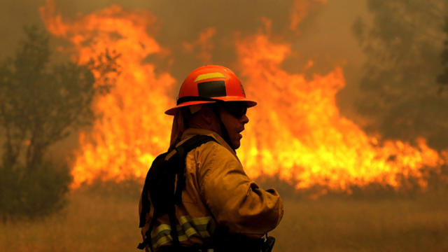 A firefighter monitors flames from the Rocky Fire as it approaches a home on July 31, 2015, in Lower Lake, California. 