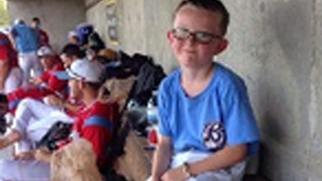 Liberal B;ue Jays bat boy Kaiser Carlile, 9, in dugout during a game 