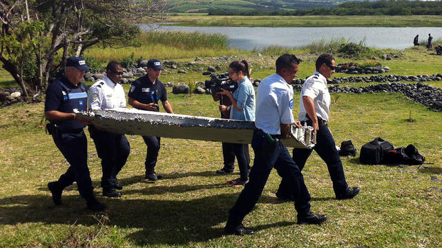 Police carry a piece of debris from an unidentified aircraft found in the coastal area of Saint-Andre de la Reunion, in the east of the French Indian Ocean island of La Reunion, July 29, 2015. 