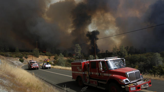 Cal Fire fire engines are seen driving along along Morgan Valley Road as smoke fills the sky during the Jerusalem Fire Aug. 11, 2015, near Lower Lake, California. 