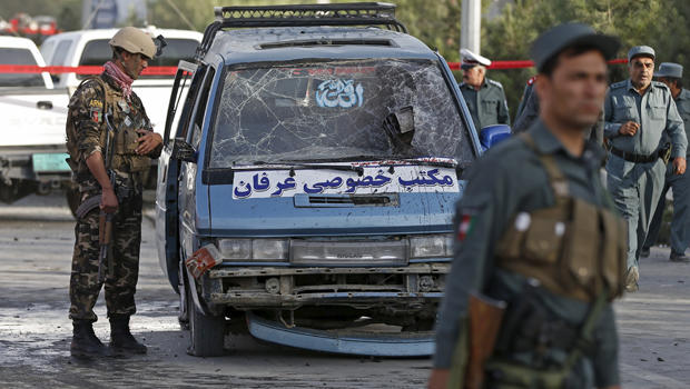 Afghan security personnel inspect a damaged vehicle at the site of a bomb blast in Kabul, Afghanistan, Aug. 22, 2015. 