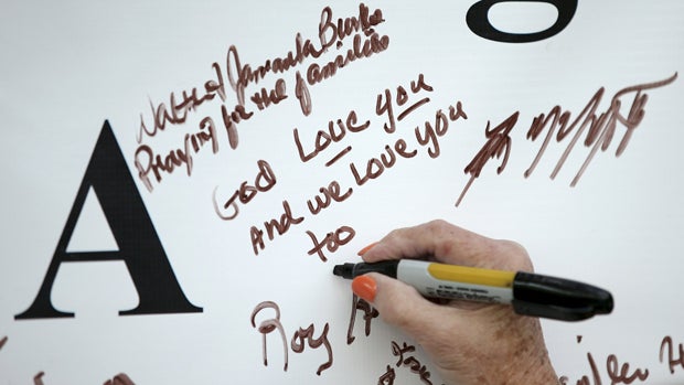 A woman signs a memorial outside of the offices of WDBJ7 in Roanoke, Virginia, for journalists who died in a shooting Aug. 26, 2015. 