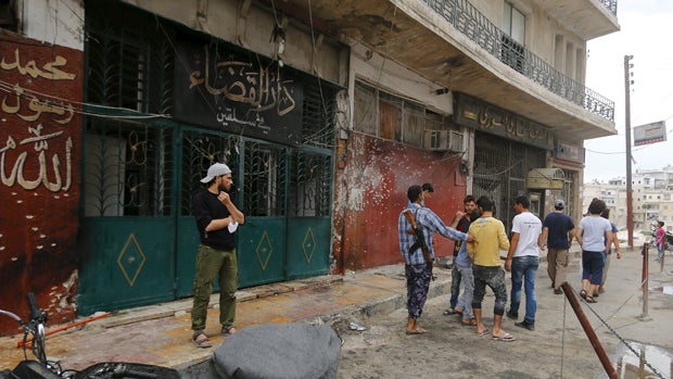 Members of al Qaeda's Nusra Front and civilians stand at the entrance of a courthouse where a suicide bomb attack took place in the town of Salqin, in Idlib, Syria, Aug. 30, 2015. 