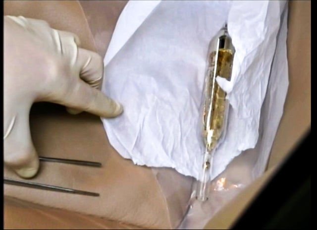 In this Feb. 19, 2015 image made from video provided by the Moldova General Police Inspectorate, an investigator looks at a vial containing cesium-135 on the driver's seat of Valentin Grossu's car following his arrest in Chisinau 