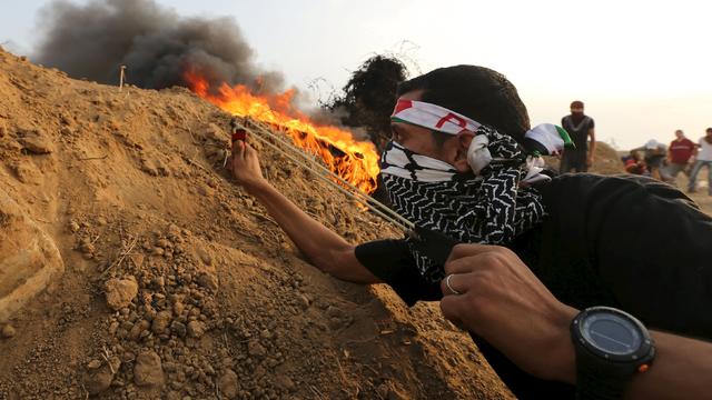 A Palestinian protester uses a slingshot to hurl stones towards Israeli troops during clashes near the border between Israel and Central Gaza Strip 