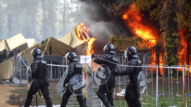Slovenian policemen walk as a fire sweeps through a migrant camp in Brezice, Slovenia. 
