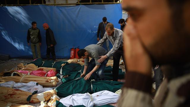 Syrian men try to identify the bodies of loved ones following a reported airstrike by Syrian government forces on the rebel-held town of Douma, on the eastern edges of the capital Damascus, Oct. 30, 2015. 