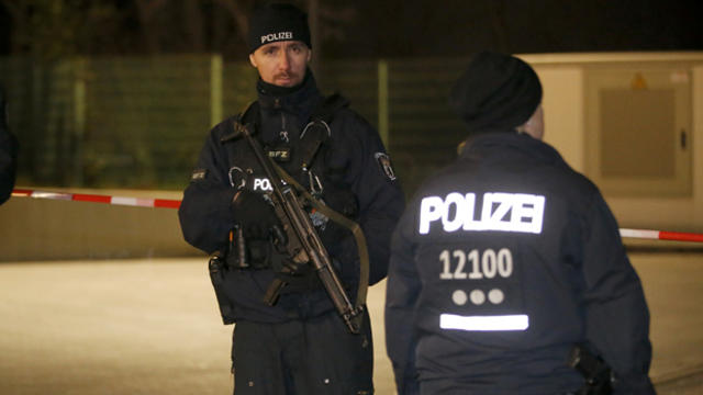 Police officers stand guard during a raid on a building in Britz, south Berlin, Germany, Nov. 26, 2015. 