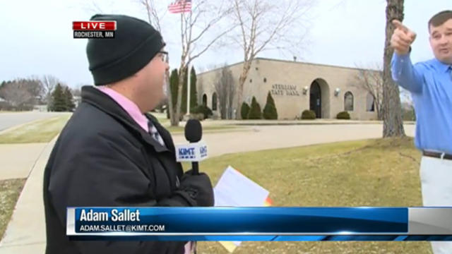 ​A bank employee interrupts a live news report to point out a suspected bank robber in Rochester, Minn., Dec. 15, 2015. 