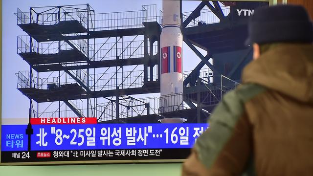 A man watches a news report on North Korea's planned rocket launch as the television screen shows file footage of North Korea's Unha-3 rocket which launched in 2012, at a railway station in Seoul 