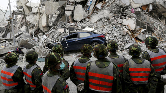 ​Soldiers stand guard in front of a damaged building and crushed vehicles after an earthquake hit Tainan, Taiwan, Feb. 6, 2016. 