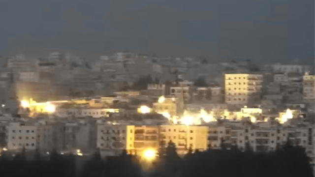 ​An image taken from video posted by Syrian opposition activists shows  buildings in Hreitan, north of Aleppo, illuminated by cluster munitions puportedly dropped by Russian warplanes 