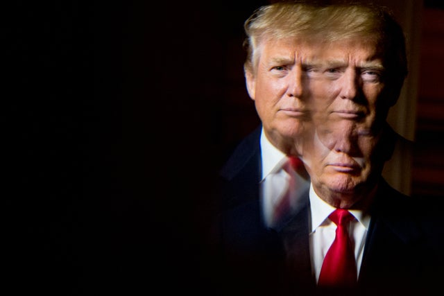 Donald Trump, seen in reflection, poses for a portrait following an interview with The Associated Press at the Trump National Golf Club in Sterling, Virginia, Dec. 2, 2015. 