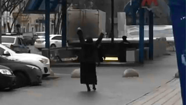 ​This screengrab from video posted to YouTube shows a woman who appears to be holding the severed head of a child while shouting at passersby outside the entrance to the Oktyabrskoye Pole metro station in northwest Moscow 