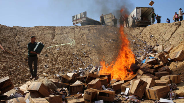 A Palestinian worker throws gasoline on burning boxes of Snickers chocolate bars on the outskirts of Gaza City March 10, 2016. 