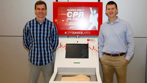 Matt Lickenbrock, left, who performed hands-only CPR on Sean Ferguson, who survived a cardiac arrest, stands next to the Hands-Only CPR Training Kiosk courtesy of the American Heart Association and Anthem Blue Cross and Blue Shield at Indianapolis Interna 