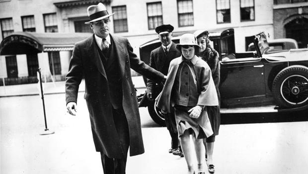 Accompanied by a bodyguard, a nurse, and a chauffeur, Gloria Vanderbilt enters the home of her mother, Gloria Morgan Vanderbilt, in Manhattan, April 22, 1935, for a Easter weekend visit. 