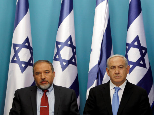 Israel's Prime Minister Benjamin Netanyahu (R) sits next to then-Foreign Minister Avigdor Lieberman 