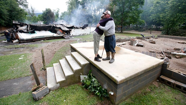Jimmy Scott gets a hug from Anna May Watson, left, as they clean up from severe flooding in White Sulphur Springs, West Virginia, June 24, 2016. 