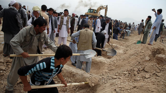 Afghan men dig graves for victims who died from a suicide attack, in Kabul, Afghanistan, Sunday, July 24, 2016. 