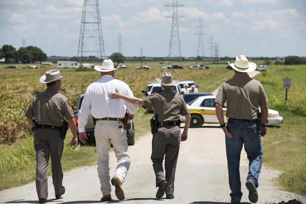 ​Texas Department of Public Safety Trooper Robbie Barrera, center right, puts her arm around Caldwell County Sheriff Daniel Law as he arrives on the scene of a hot air balloon crash July 30, 2016, near Lockhart, Texas, causing what authorities described as a "significant loss of life." 
