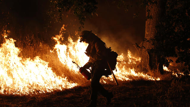 A firefighter with the Marin County Fire Department’s Tamalpais Fire Crew ignites a backfire with a driptorch as he battles the Valley Fire on Sept. 13, 2015, near Middletown, California. 