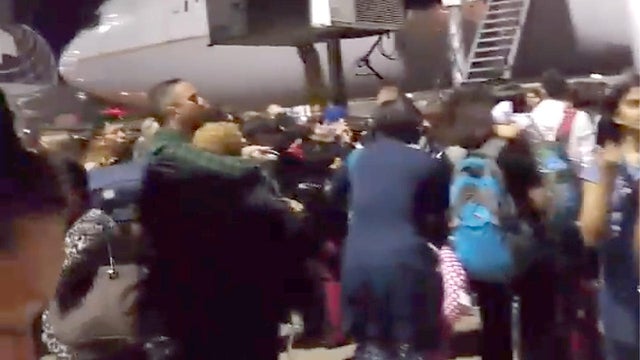 Passengers stand on a tarmac at Los Angeles International Airport late on Aug. 28, 2016, after at least one terminal was evacuated following unconfirmed reports of an active shooter in the building 