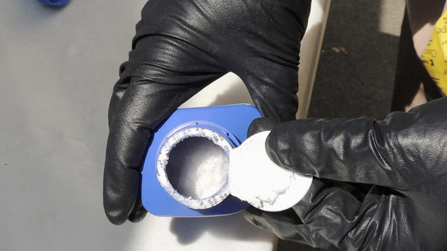 A member of the Royal Canadian Mounted Police opens a printer ink bottle containing the opioid carfentanil imported from China 