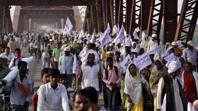 Hindu pilgrims hold religious flags and walk on a crowded bridge after a stampede on the same bridge on the outskirts of Varanasi, India, Oct. 15, 2016. 