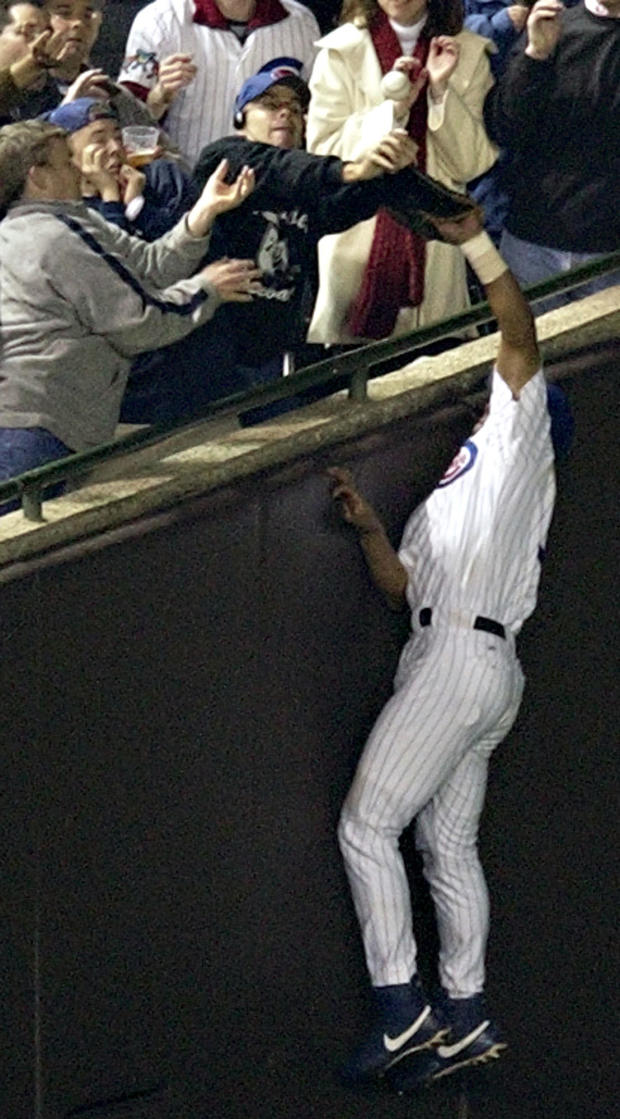 Chicago Cubs left fielder Moises Alou reaches into the stands unsuccessfully for a foul ball as Cubs fan Steve Bartman also reaches for the ball during the eighth inning of Game 6 of the National League Championship Series between the Cubs and the Florida 