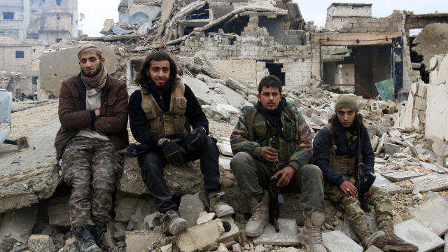 Rebel fighters sit on the rubble of damaged buildings as they wait to be evacuated from a rebel-held sector of eastern Aleppo, Syria, Dec. 16, 2016. 
