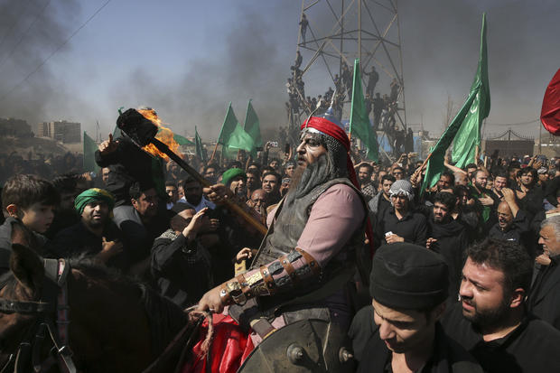 A Shiite re-enacts the events of Ashoura while Iranian and Iraqi Shiite Muslims mourn in a procession in southern Tehran, Iran, Oct. 12, 2016. Shiites mark Ashoura, the tenth day of the Muslim month of Muharram, to commemorate the martyrdom of Imam Hussei 