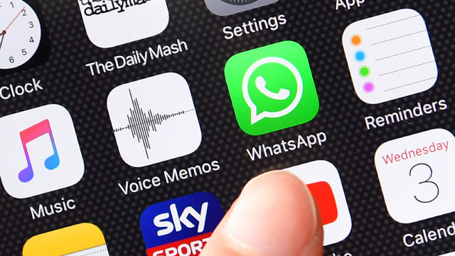 A person’s finger is posed next to the WhatsApp app logo on an iPhone on Aug. 3, 2016, in London, England. 