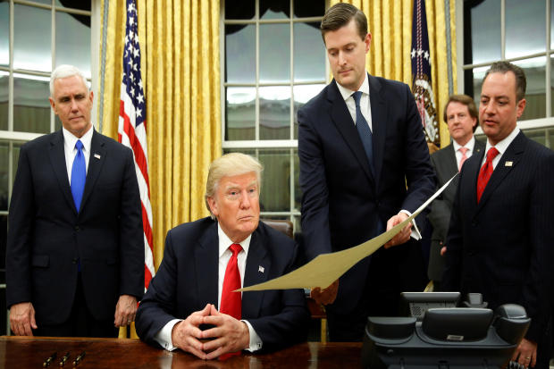 White House staff secretary Rob Porter, third from right, gives President Trump, flanked by Vice President Mike Pence and Chief of Staff Reince Priebus, right, the document confirming James Mattis as his secretary of defense, Mr. Trump's first signing in the Oval Office in Washington Jan. 20, 2017. 
