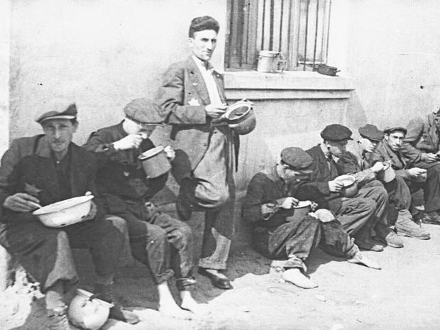 lodz-ghetto-08-group-of-men-alongside-building-eating-from-pails-henryk-ross.jpg 