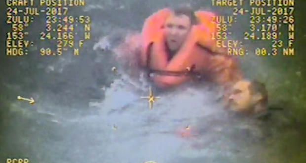 The captain of the fishing vessel Grayling, left, rescues one of his crewmen after the vessel capsized in the Kupreanof Strait near Raspberry Island, Alaska, in this still image from video taken on July 24, 2017, by the Coast Guard. 
