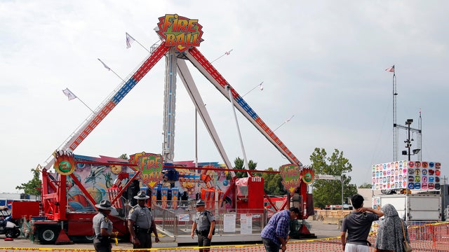 Passers-by look at the Fire Ball ride as Ohio State Highway Patrol troopers stand guard at the Ohio State Fair July 27, 2017, in Columbus, Ohio. 