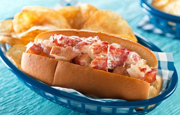 A delicious lobster roll with potato chips. 