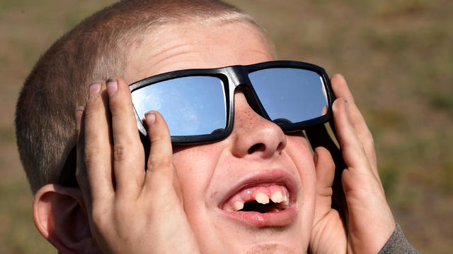 Cooper Jackson tries out his new solar glasses in a designated eclipse viewing area in a campground near Guernsey 