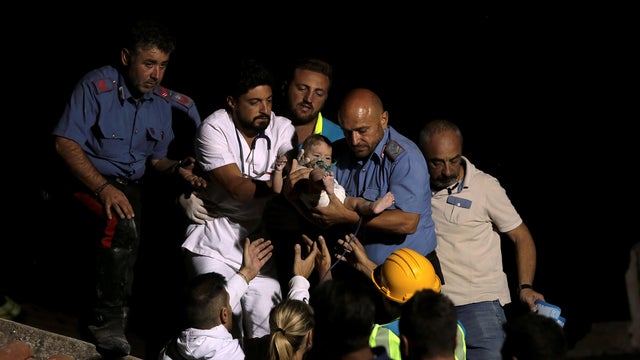Italian Carabinieri police officer and a doctor carry a child after an earthquake hit the island of Ischia, off the coast of Naples 