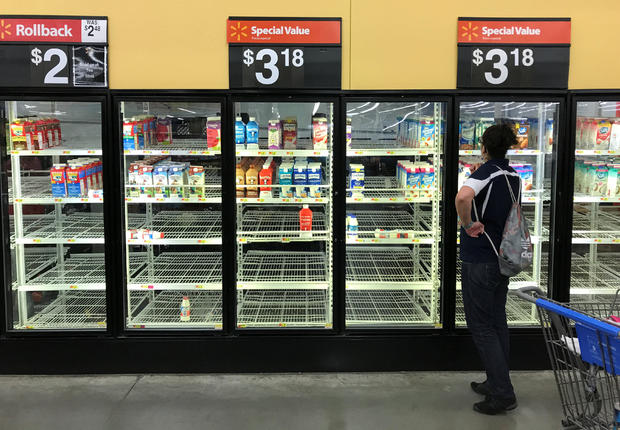 A unidentified woman looks over bare refrigerator shelves in a Walmart store in Houston 
