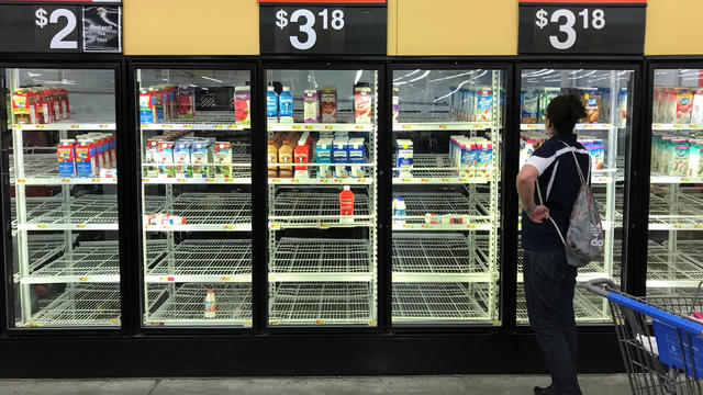 A unidentified woman looks over bare refrigerator shelves in a Walmart store in Houston 