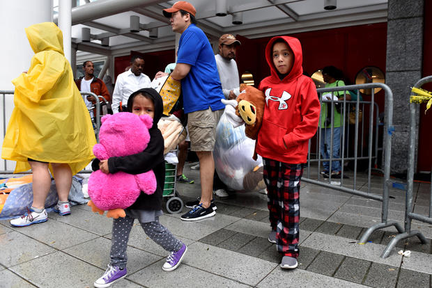 Evacuees carry their belongings outside of the George R. Brown Convention Center where over 9,000 people have taken refuge 