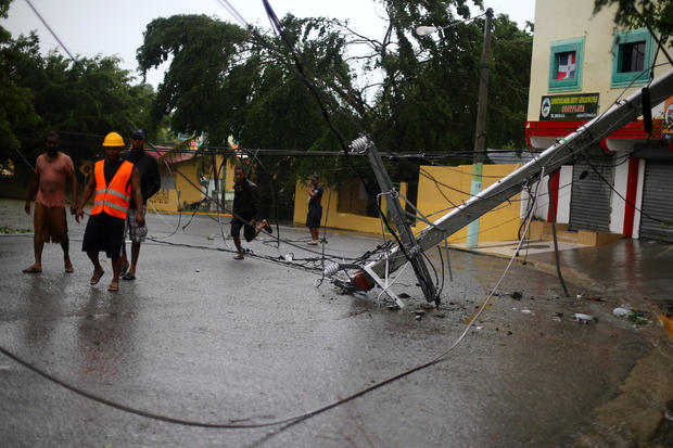 Locals walk past a fallen power pole as Hurricane Irma moves off the northern coast of the Dominican Republic, in Puerto Plata 