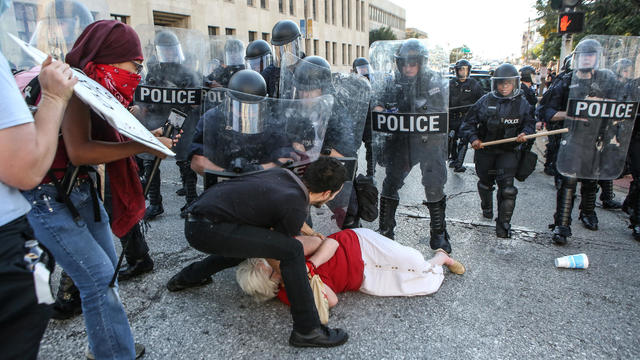 A woman who was pushed down by police is helped by a protester while police try to desperse a crowd, after a not guilty verdict in the murder trial of Jason Stockley in St. Louis 