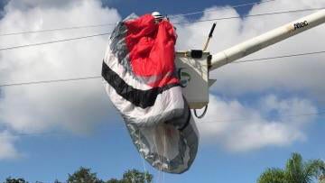 A utility worker untangles a paraglider's equipment from power lines in St. Petersburg, Florida, on Sept. 26, 2017. 