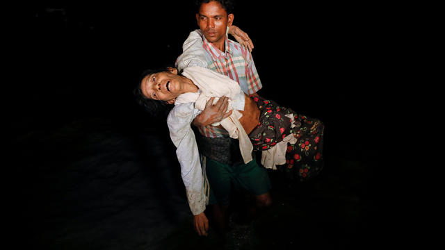 Nobi Hossain wades through the water carrying his elderly relative Sona Banu as hundreds of Rohingya refugees arrive under the cover of darkness by wooden boats from Myanmar to the shore of Shah Porir Dwip 