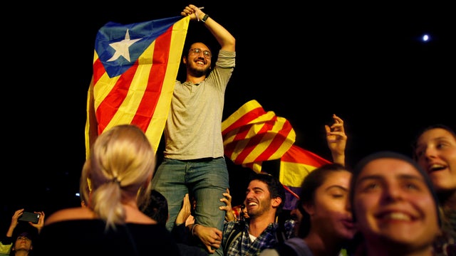 A man holds an Estelada (Catalan separatist flag) as people gather at Plaza Catalunya after voting ended for the banned independence referendum in Barcelona 