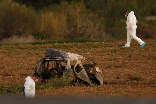 Forensic experts walk in a field after a powerful bomb blew up a car killing investigative journalist Daphne Caruana Galizia in Bidnija 